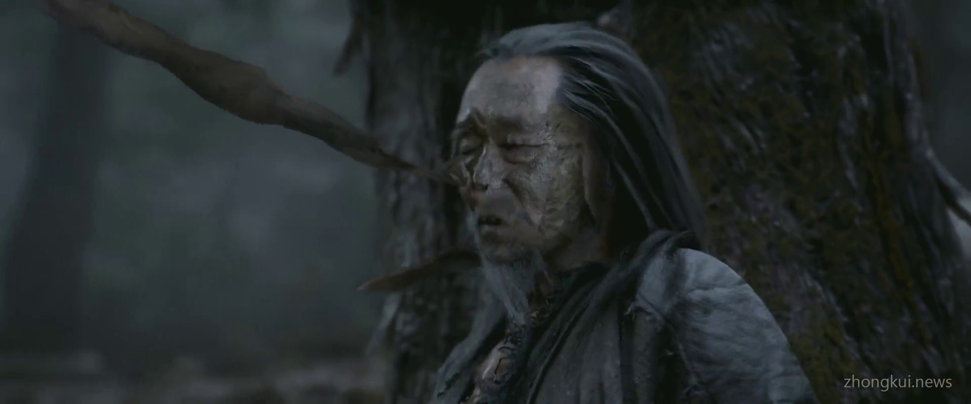 Close view of an emaciated old man with bark-like skin and twigs caught in his hair, laughing in a forest
